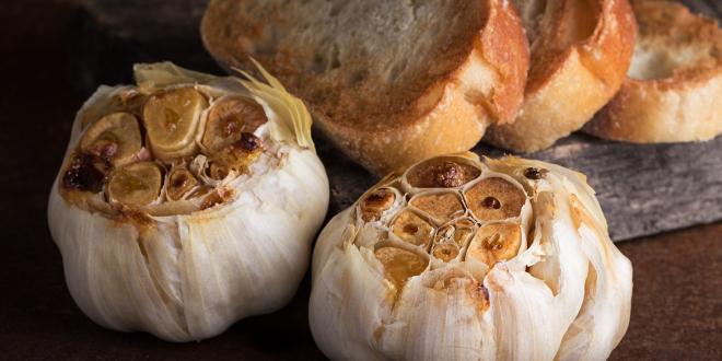 heads of roasted garlic with slices of toasted bread.