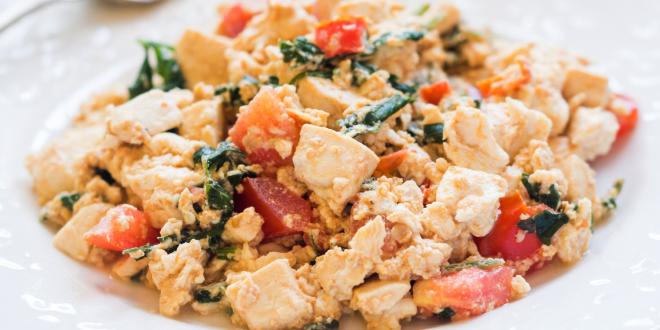a plate of scrambled tofu with greens and tomatoes