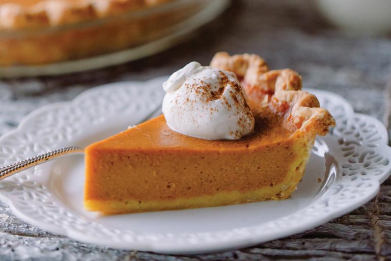 a slice of pumpkin pie with a dollop of whipped cream