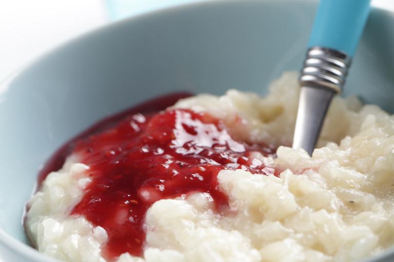 a bowl of rice pudding drizzled with a berry sauce