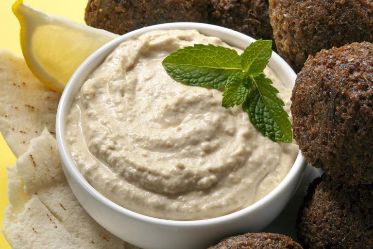 a bowl of creamy hummus and some falafel